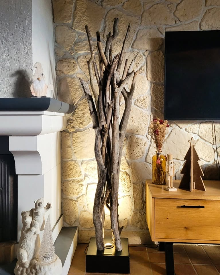 Création lumineuse en bois flotté devant un mur en pierre